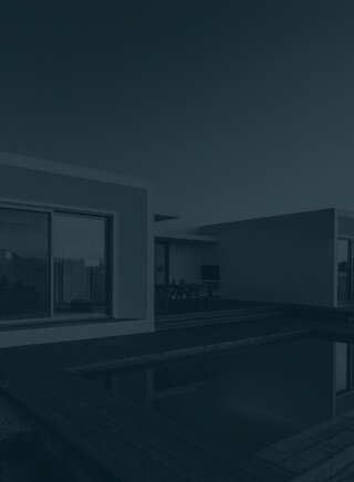 Contemporary single-story house with a cubic design and glass windows, next to a private pool on a wooden deck